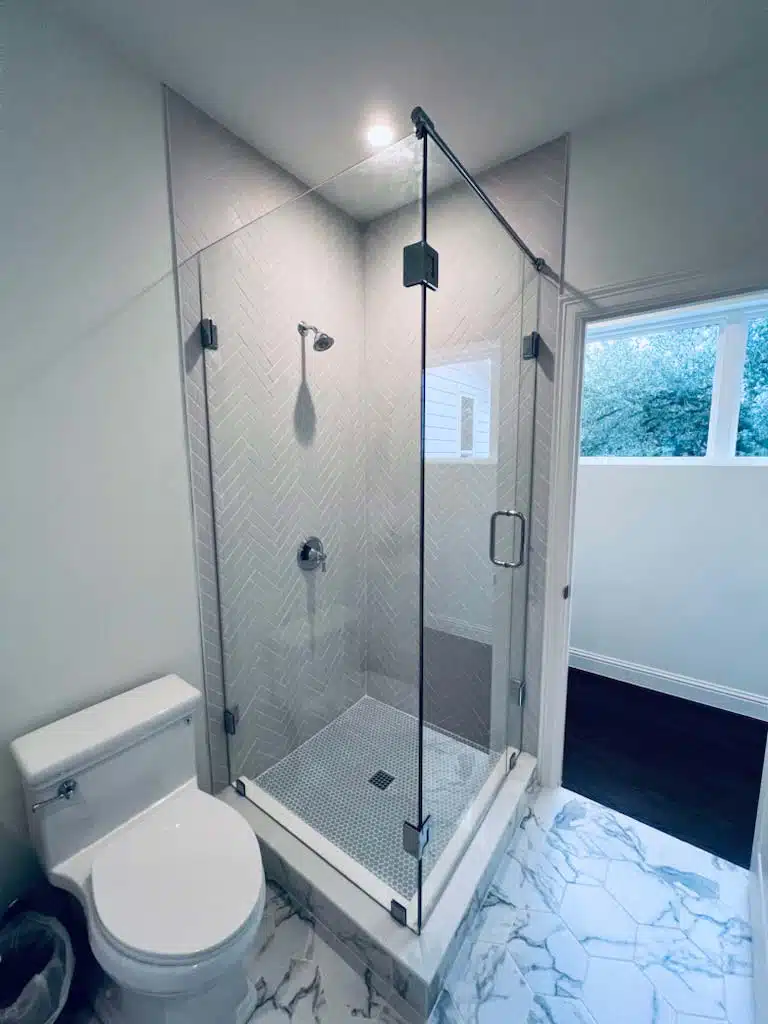 Standing 90-degree shower with sliding door connected to glass panel